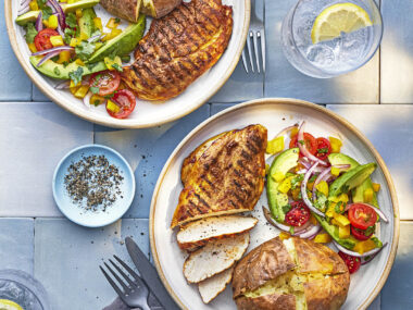 two plates with grilled chicken with avocado salad