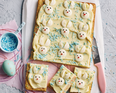 Easter baking idea: A rectangular slab of blondies with white chocolate icing topped with white chocolate in the shape of rabbits - the perfect Easter baking treat!