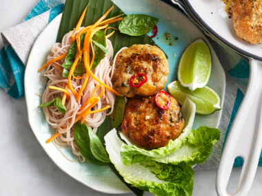 Two Thai fish cakes in a bowl with vermicelli salad, carrots and lettuce.